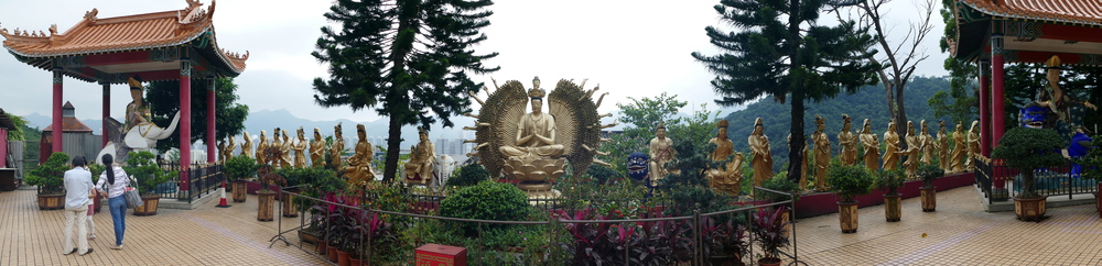 Very wide shot showing a thousand-armed Buddha statue with apsaras.