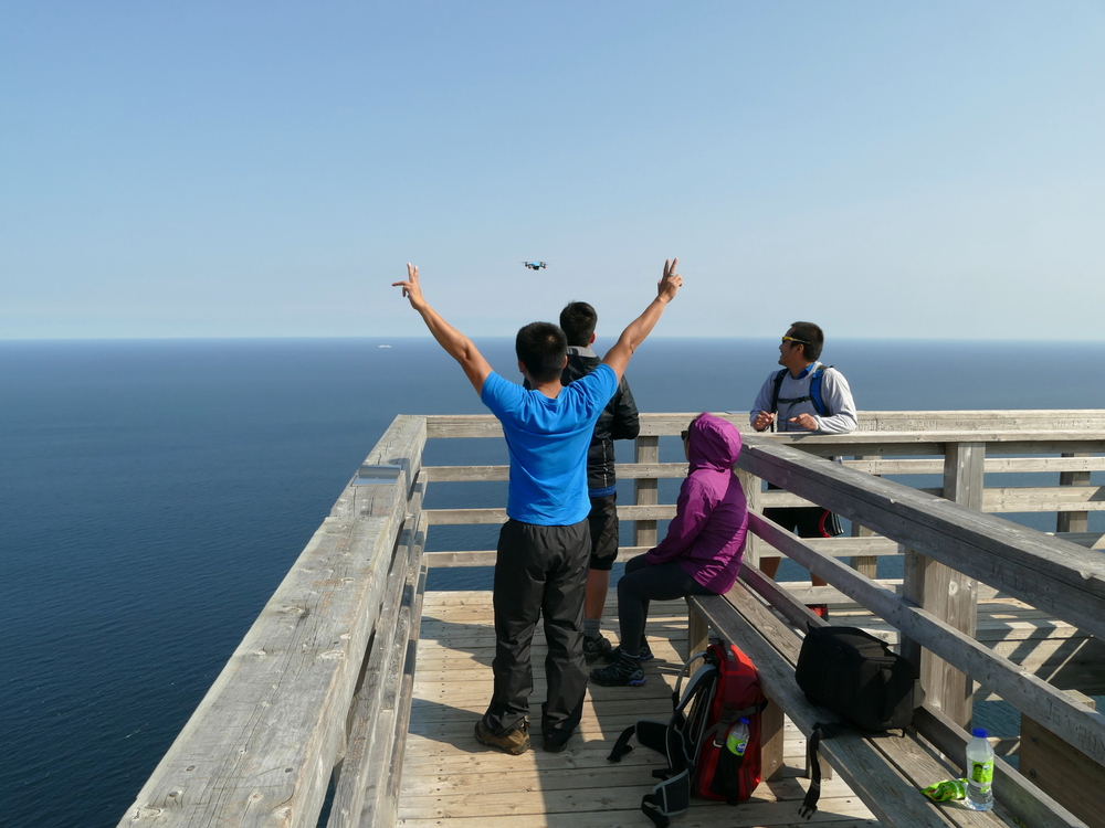 four people watching and waving to their drone