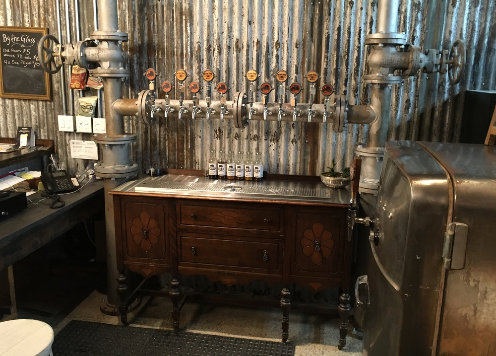 multiple beer taps mounted on a large diameter flanged pipe