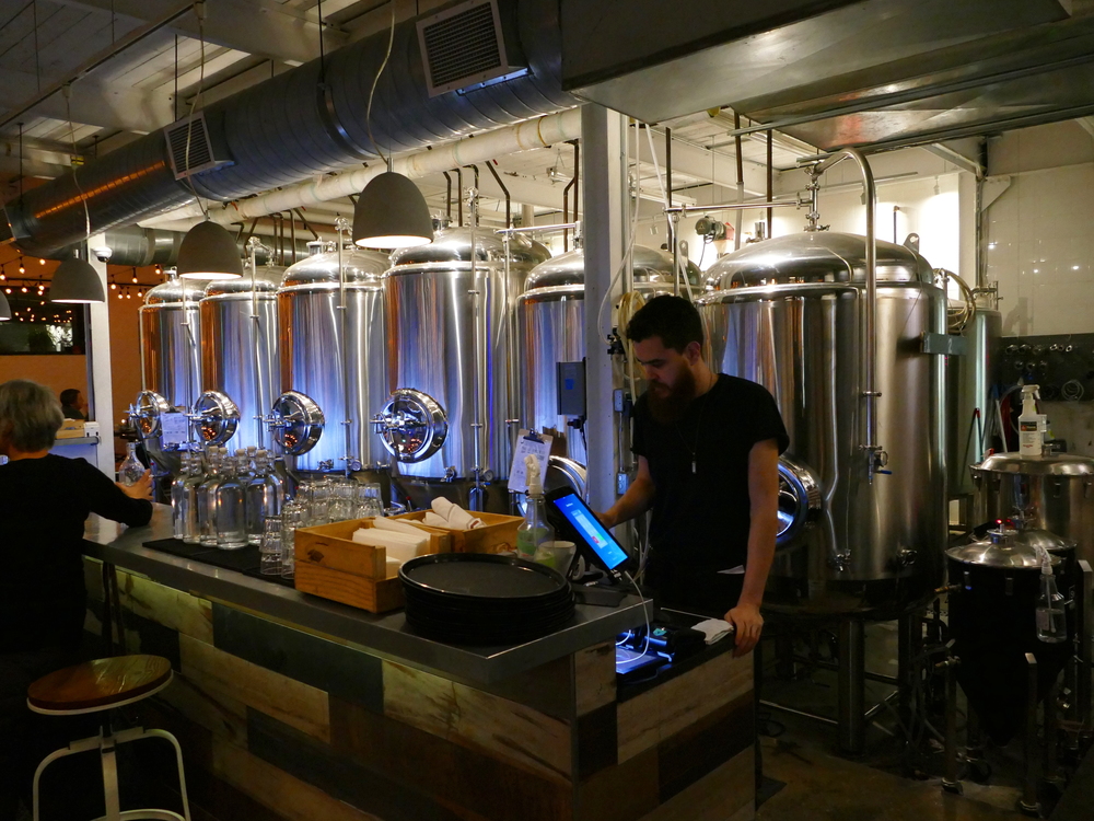 A bar with quite a few stainless steel tanks behind it