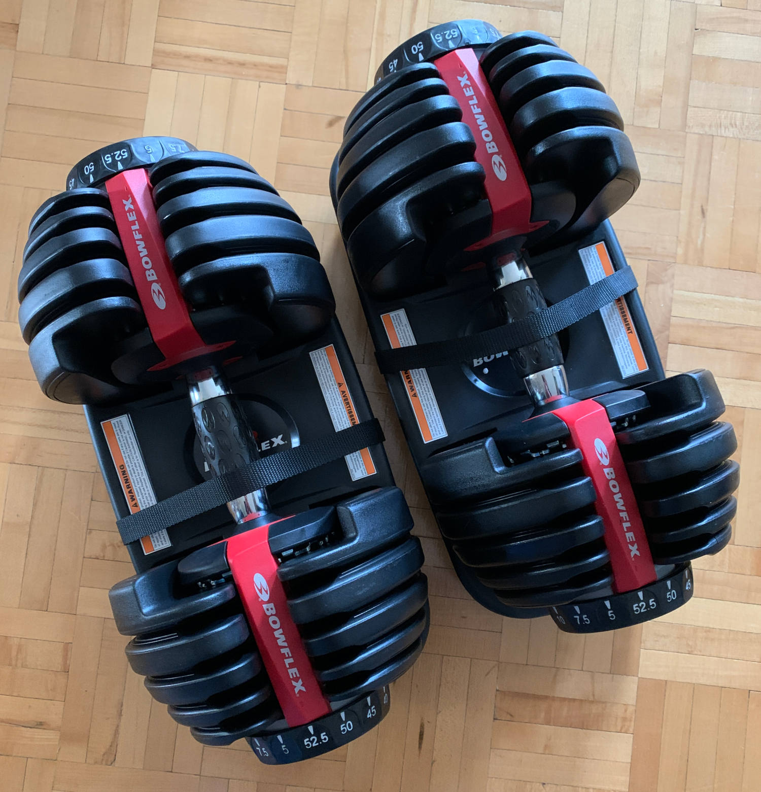 somewhat complicated adjustable dumbbells each with number dials on both ends