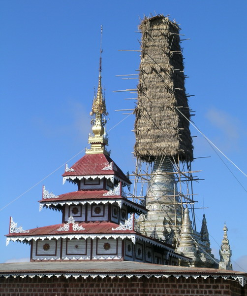Temple spires, one enclosed in bamboo and thatch.