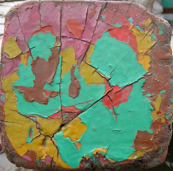 several colours of paint flaking off the end of a wood beam