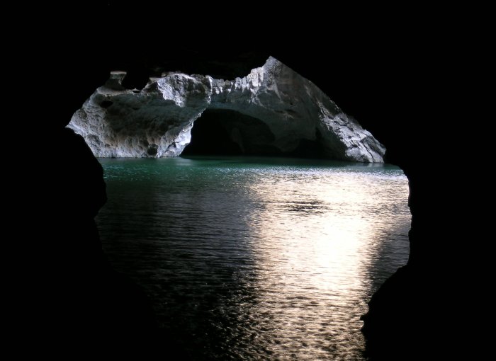 Underground river through a cave with daylight streaming in.