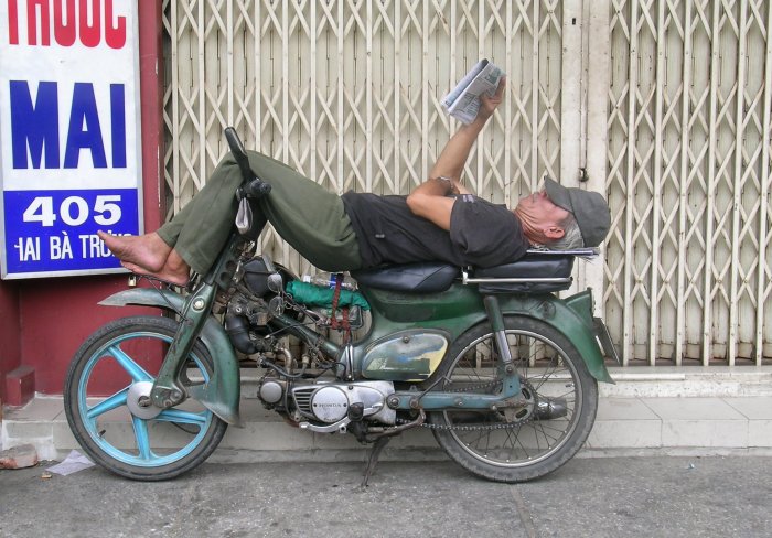 Moto driver lying on his motorcycle reading the paper