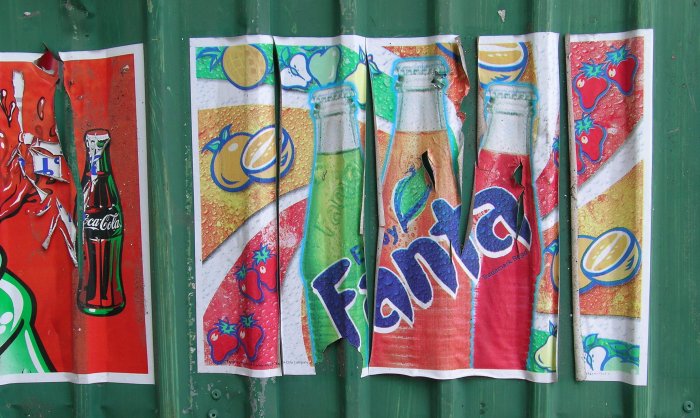 Colourful, peeling Fanta ad on a green corrugated metal wall