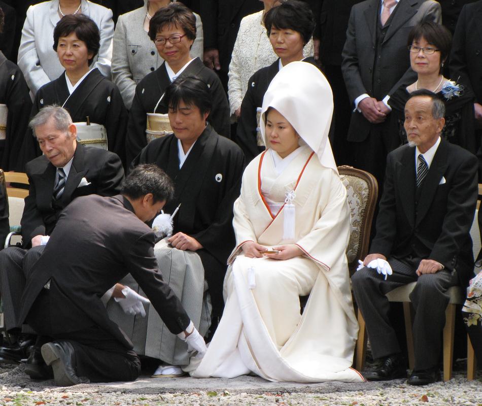 A couple in Japanese formal-wear sit as part of a wedding ceremony